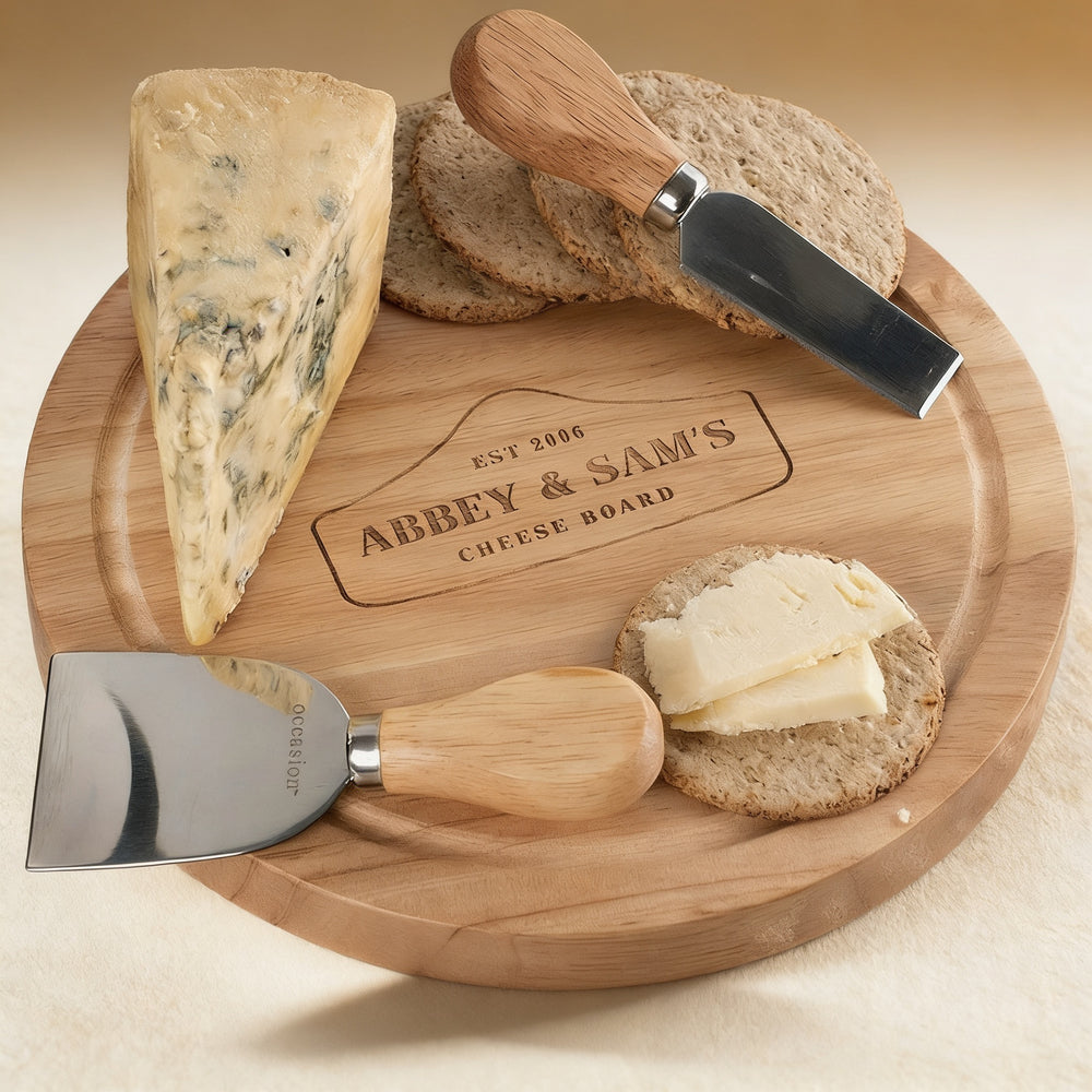 Personalized solid wood cheese board engraved with a monogram, open to reveal four wood-handled utensils, 10-inch diameter