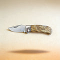 Custom engraved pocket knife with monogram, shown closed on a dark wood surface