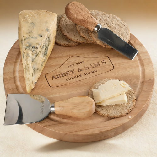 Personalized solid wood cheese board engraved with a monogram, open to reveal four wood-handled utensils, 10-inch diameter