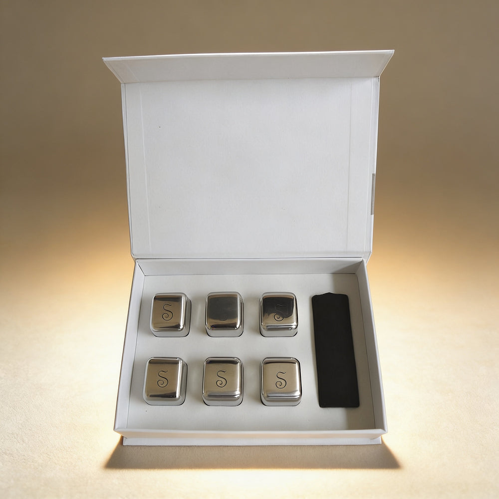 Personalized stainless steel ice cubes beside a whiskey glass, laser engraved gift set