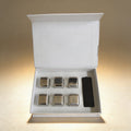 Personalized stainless steel ice cubes beside a whiskey glass, laser engraved gift set