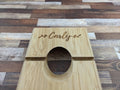 Custom engraved bamboo wine balancer holding a bottle at an angle, natural bamboo finish