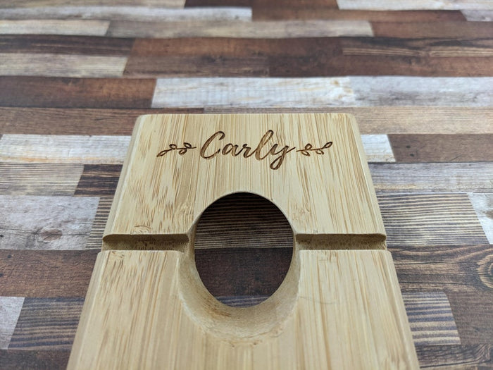 Custom engraved bamboo wine balancer holding a bottle at an angle, natural bamboo finish