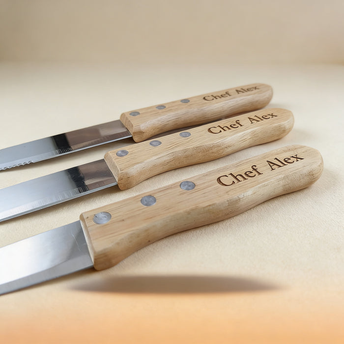 Set of 6 laser-engraved steak knives with natural maple wood handles arranged on a wooden surface