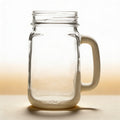 Custom engraved glass mason jar mug with monogram, shown from front on wooden surface
